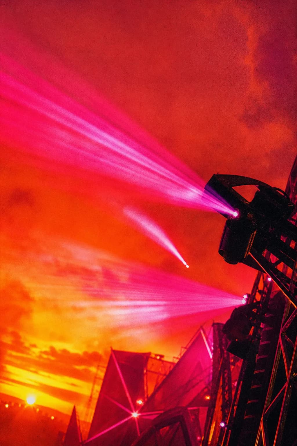 Pink and orange stage lights and lasers cutting through haze above the Sun Stage